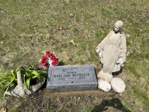 A statue of the Virgin Mary next to a headstone that reads "Mary Jane Heythaler."